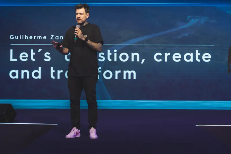 Gui Zanoni no palco do Kick-off Electrolux 2025, com o telão Let's question, create and transform