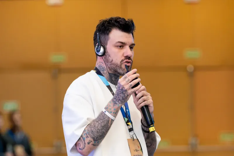 Gui Zanoni de perto, falando ao microfone com fone de tradução