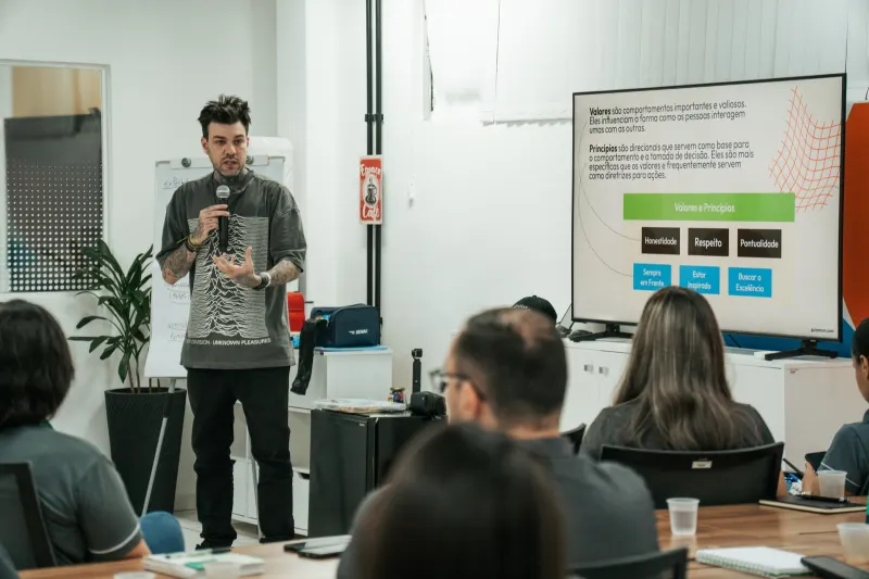 Gui Zanoni conduzindo um workshop em sala, com o grupo sentado à frente
