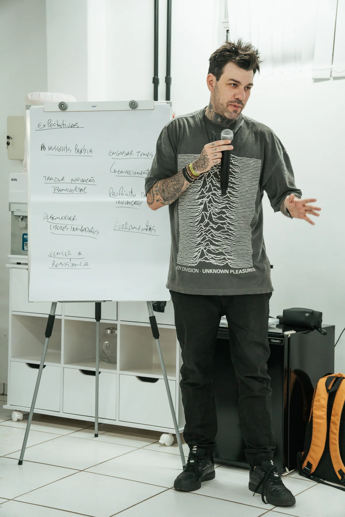 Gui Zanoni conduzindo uma atividade com microfone e flip chart.